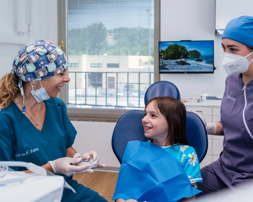 Bambina sulla poltrona del dentista che parla con una denstista