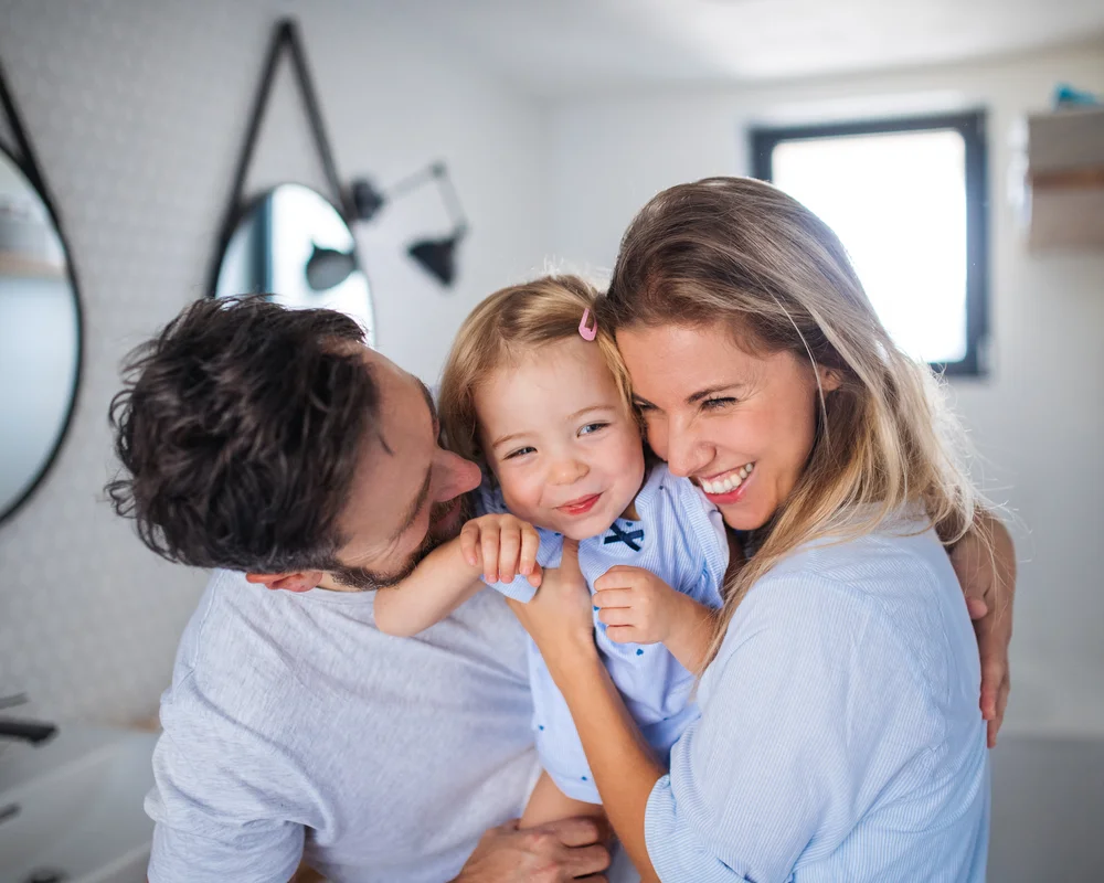 Padre madre e figlia che si abbracciano e sorridono