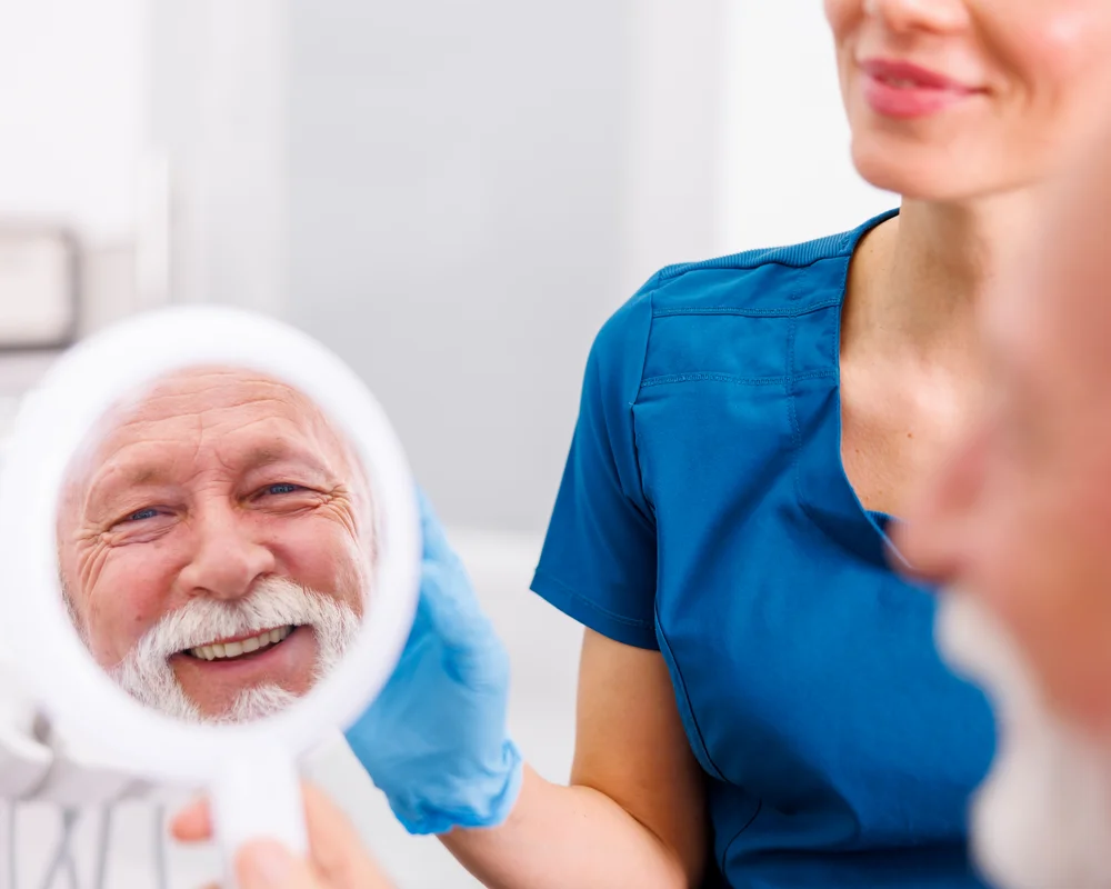 Uomo anziano che si specchia dal dentista e sorride